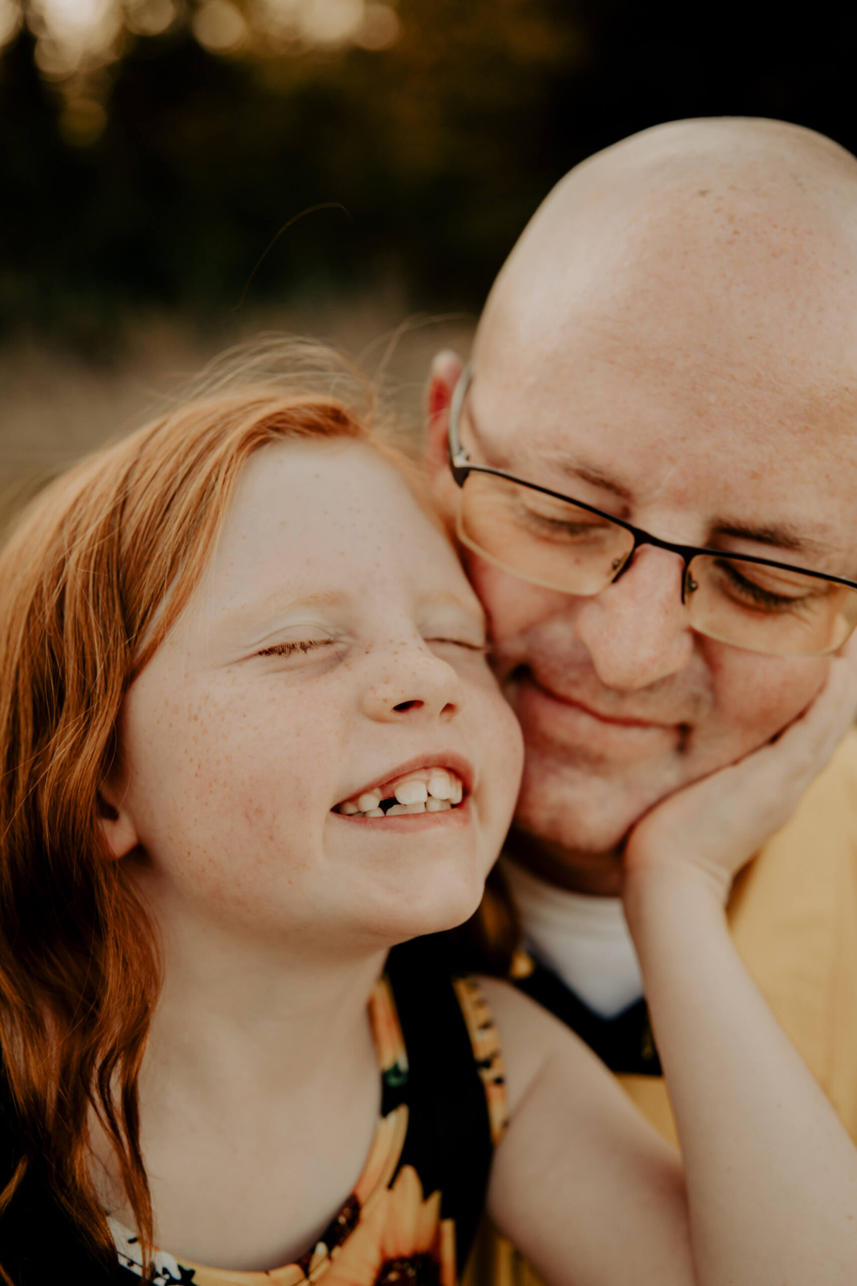 Sweet image of a young redheaded girl with freckles snuggling with her Dad.